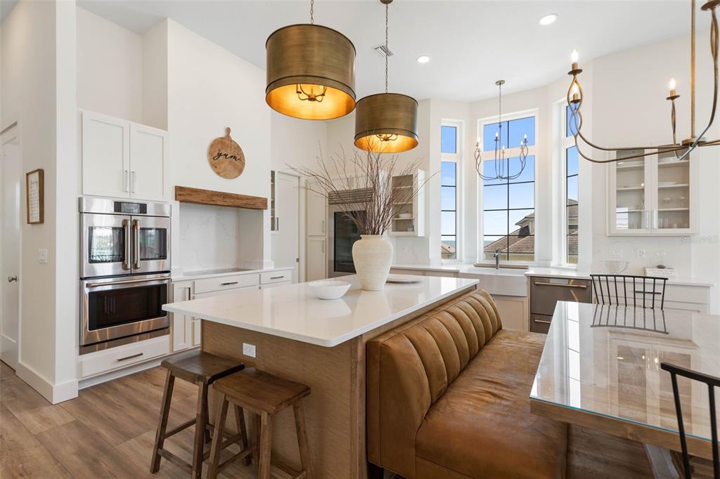 A kitchen features a large island with a brown leather bench and two wooden stools — 546 CINNAMON BEACH LANE, PALM COAST, FL
