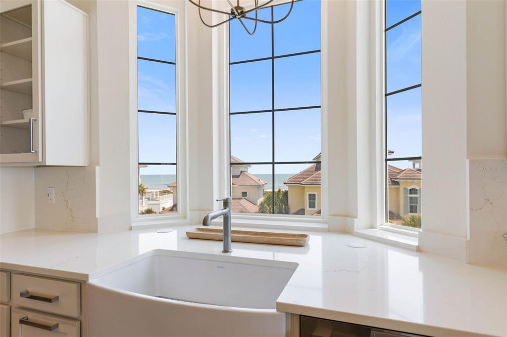 A kitchen sink sits before a bay window with views of houses and the ocean — 546 CINNAMON BEACH LANE, PALM COAST, FL
