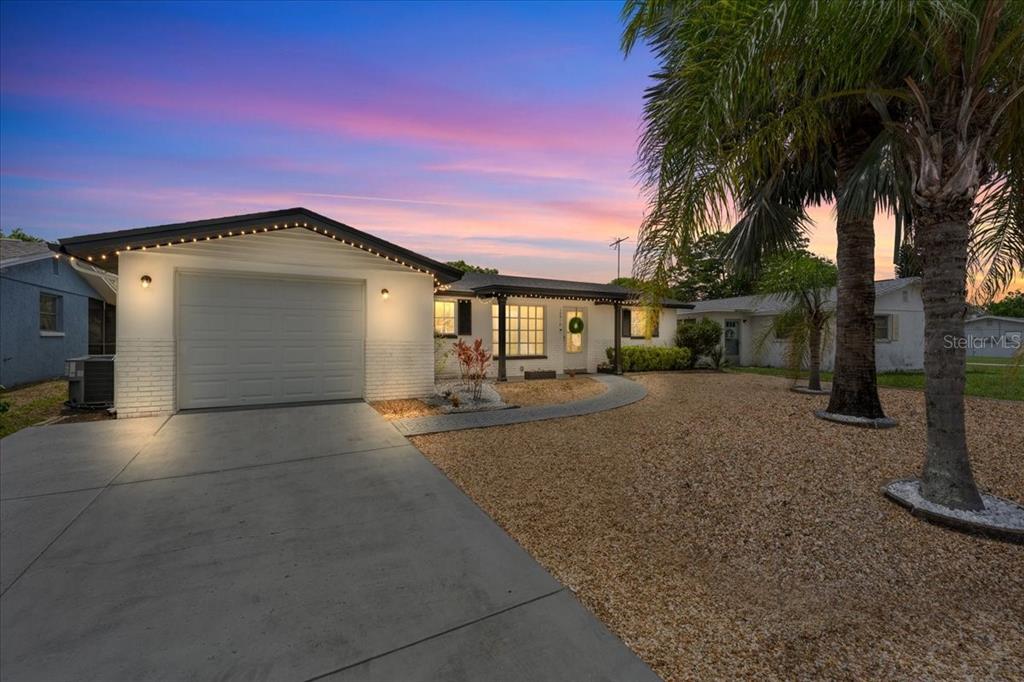 A single-story house with a white brick exterior, a garage, and a gravel front yard — 10914 OAKDALE AVENUE, PORT RICHEY, FL