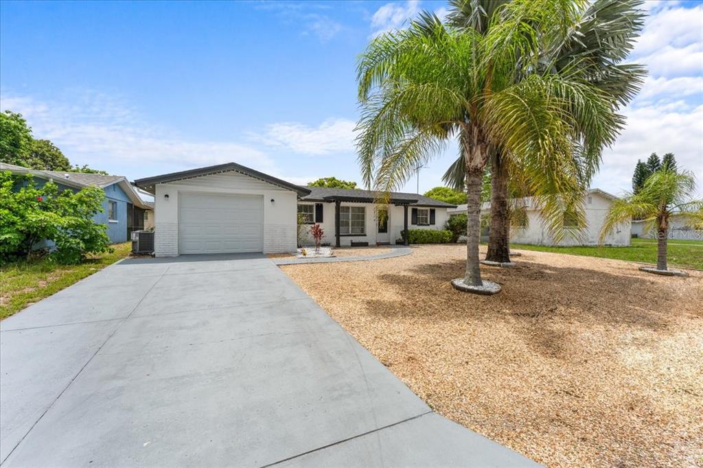 A single-story house with a white exterior, a garage, and palm trees in the yard — 10914 OAKDALE AVENUE, PORT RICHEY, FL