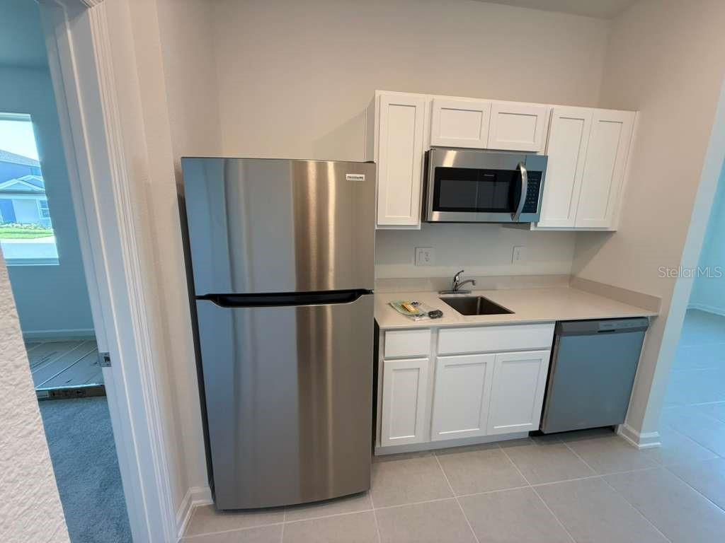 A small kitchenette features white cabinets, stainless steel appliances, and a sink on light countertops — 3483 MUD CANYON DRIVE UNIT A, DAVENPORT, FL