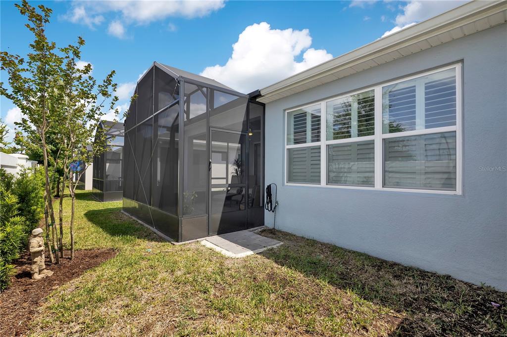 A screened-in patio with paver flooring, outdoor furniture, and a view of a privacy wall — 15157 AQUA SOL LANE, WINTER GARDEN, FL