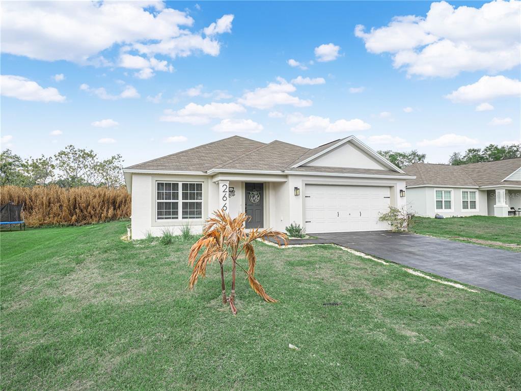 A single-story house with a white stucco exterior, a two-car garage, and a brown roof — 266 S LAKE AVENUE, FROSTPROOF, FL