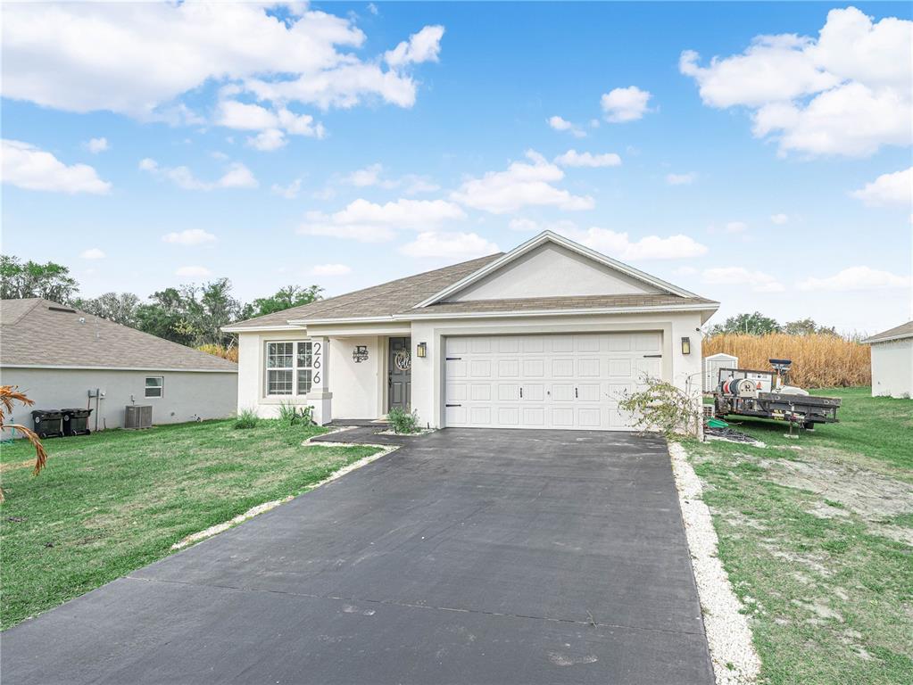 A single-story house with a white exterior, a two-car garage, and a paved driveway — 266 S LAKE AVENUE, FROSTPROOF, FL