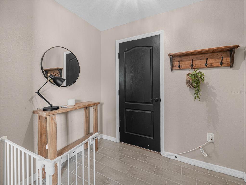 An entryway features a black door, a wooden console table, a mirror, and wall hooks — 266 S LAKE AVENUE, FROSTPROOF, FL