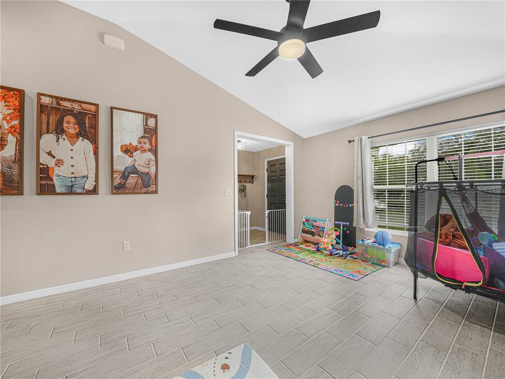 A living room with light tile flooring, a ceiling fan, and a children's play area — 266 S LAKE AVENUE, FROSTPROOF, FL
