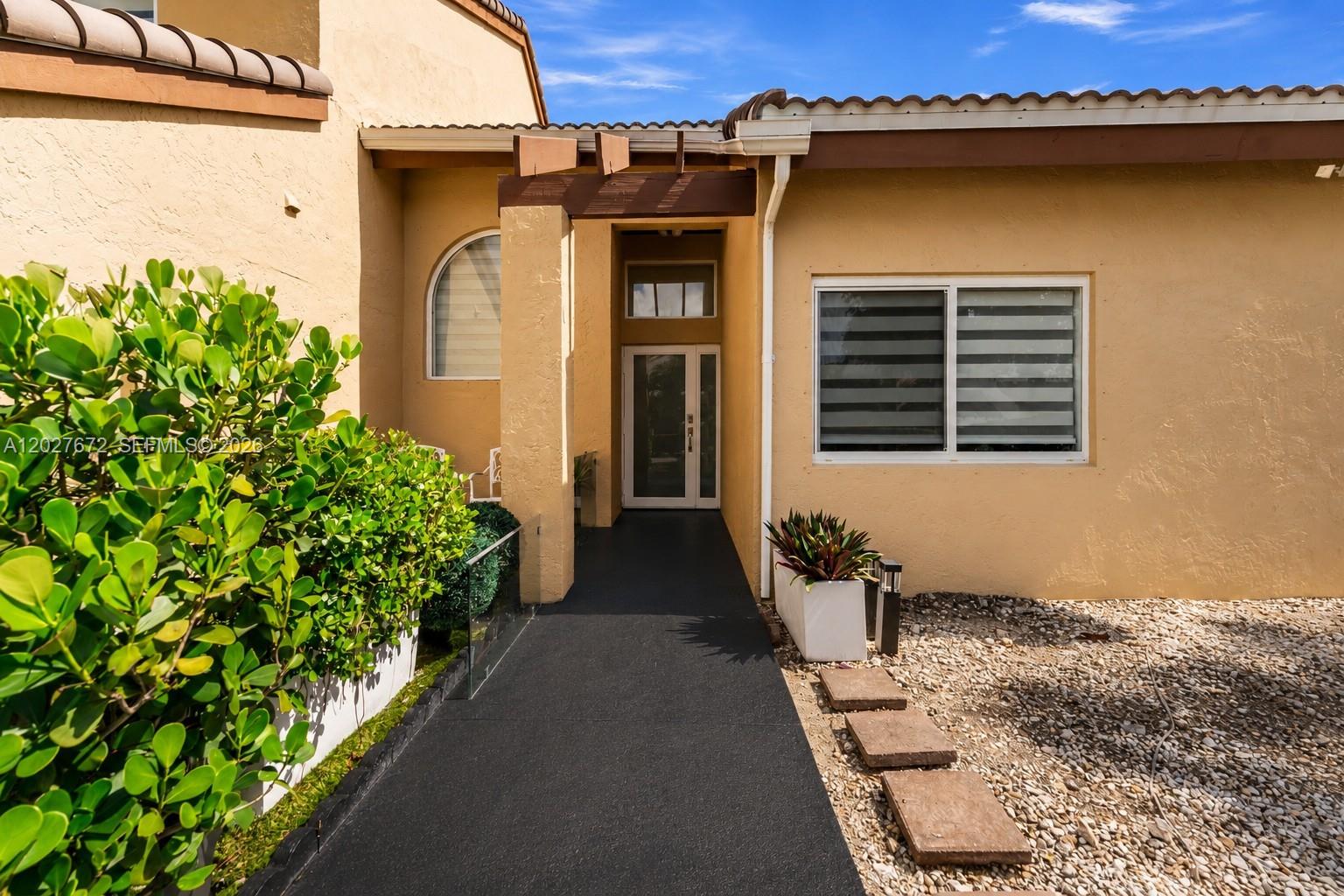 The exterior of a tan house features a dark walkway leading to the front entrance — 12745 SW 62nd Ter, Miami FL 33183, MIAMI, FL