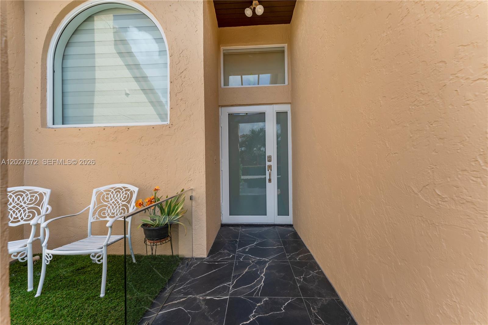An exterior entryway features a glass-paneled door, black marble-look floor tiles, and white chairs — 12745 SW 62nd Ter, Miami FL 33183, MIAMI, FL