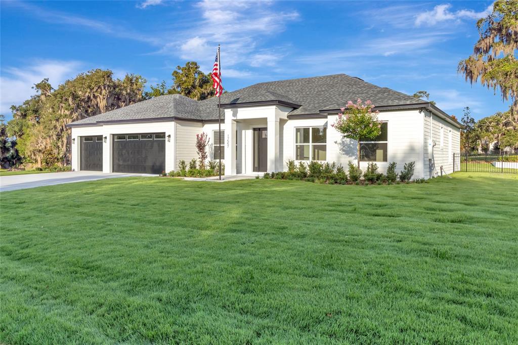 A white single-story house with a dark roof, two-car garage, and a front lawn — 17557 NINTH STREET, MONTVERDE, FL