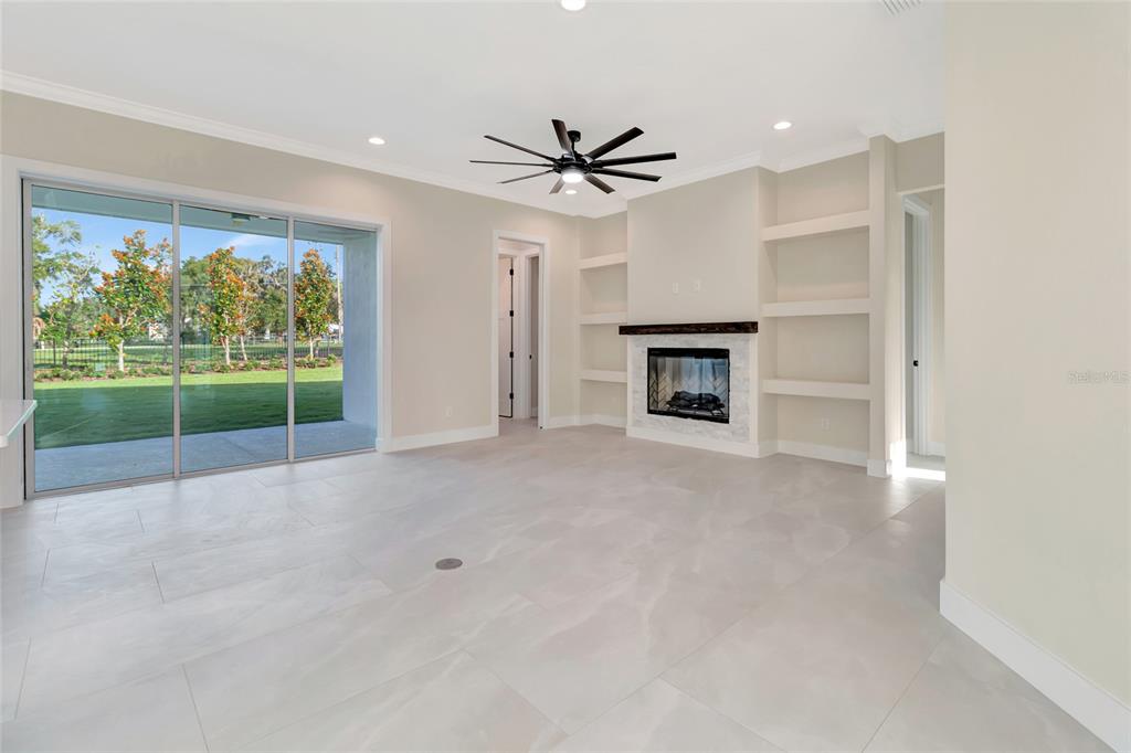 A living room features light tile flooring, a fireplace with built-in shelves, and sliding glass doors — 17557 NINTH STREET, MONTVERDE, FL