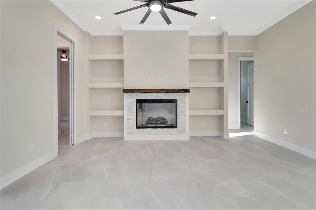 A living room features a fireplace with a wood mantel, built-in shelves, and tile flooring — 17557 NINTH STREET, MONTVERDE, FL