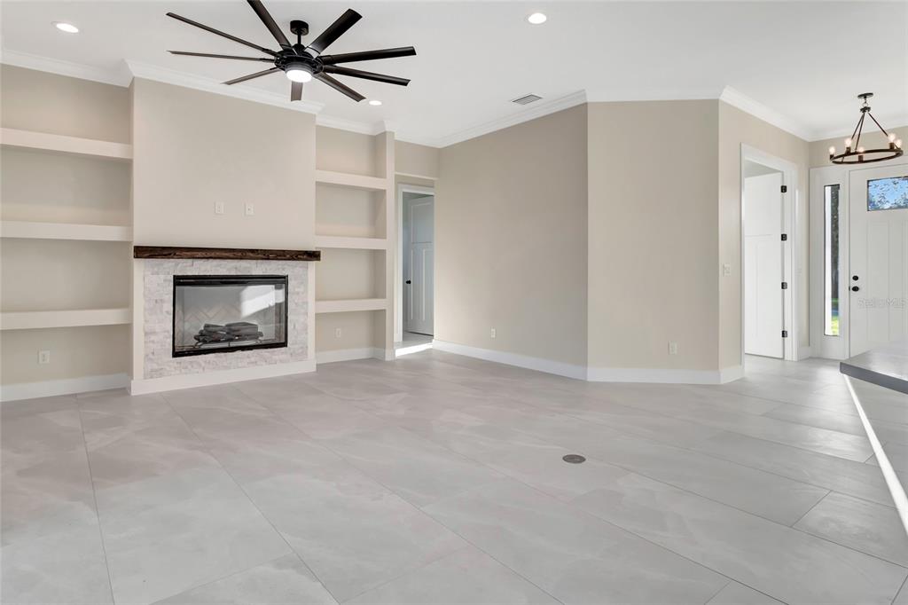 A living room features light tile floors, a fireplace with built-in shelves, and a ceiling fan — 17557 NINTH STREET, MONTVERDE, FL
