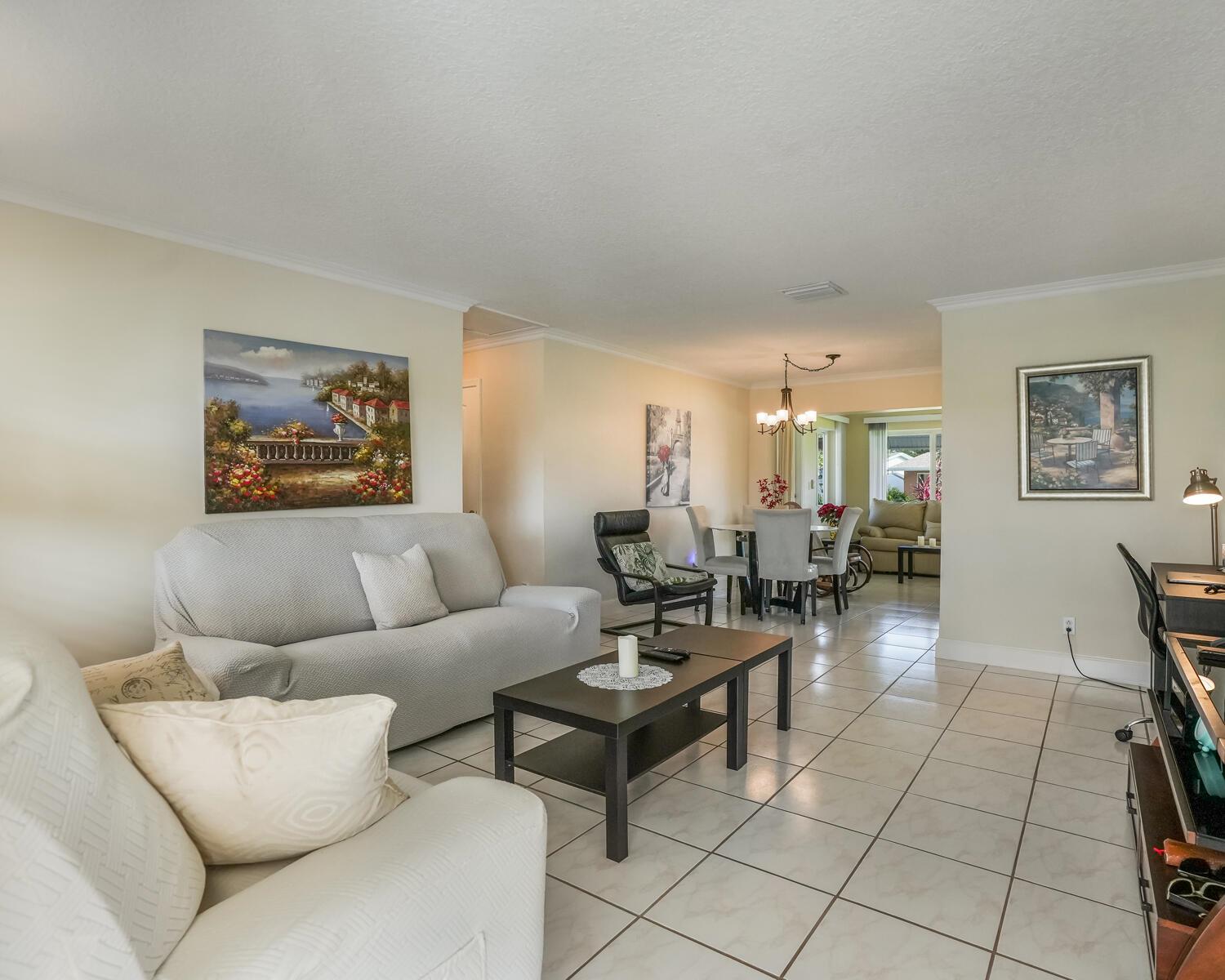 A living room with tile floors, a sofa, a coffee table, and an adjacent dining area — 4712 Mainland Drive, Tamarac FL 33319, TAMARAC, FL