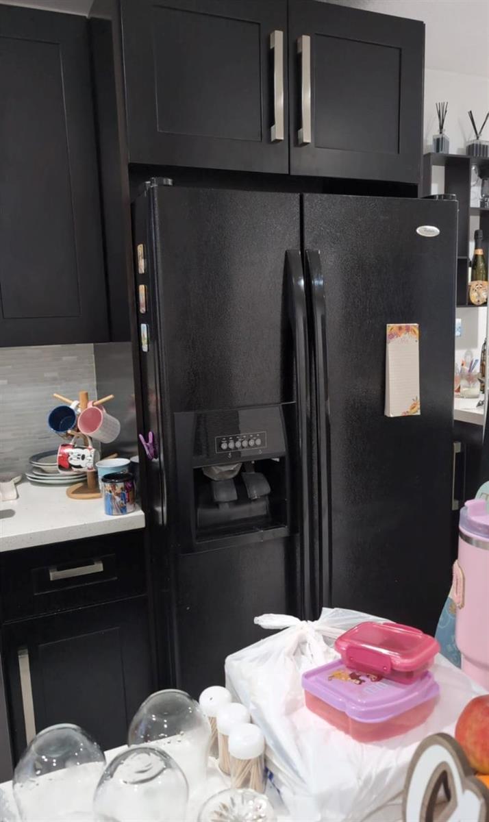 A black side-by-side refrigerator is positioned between dark cabinets in a kitchen — 4655 Palm Avenue, Hialeah FL 33012, HIALEAH, FL