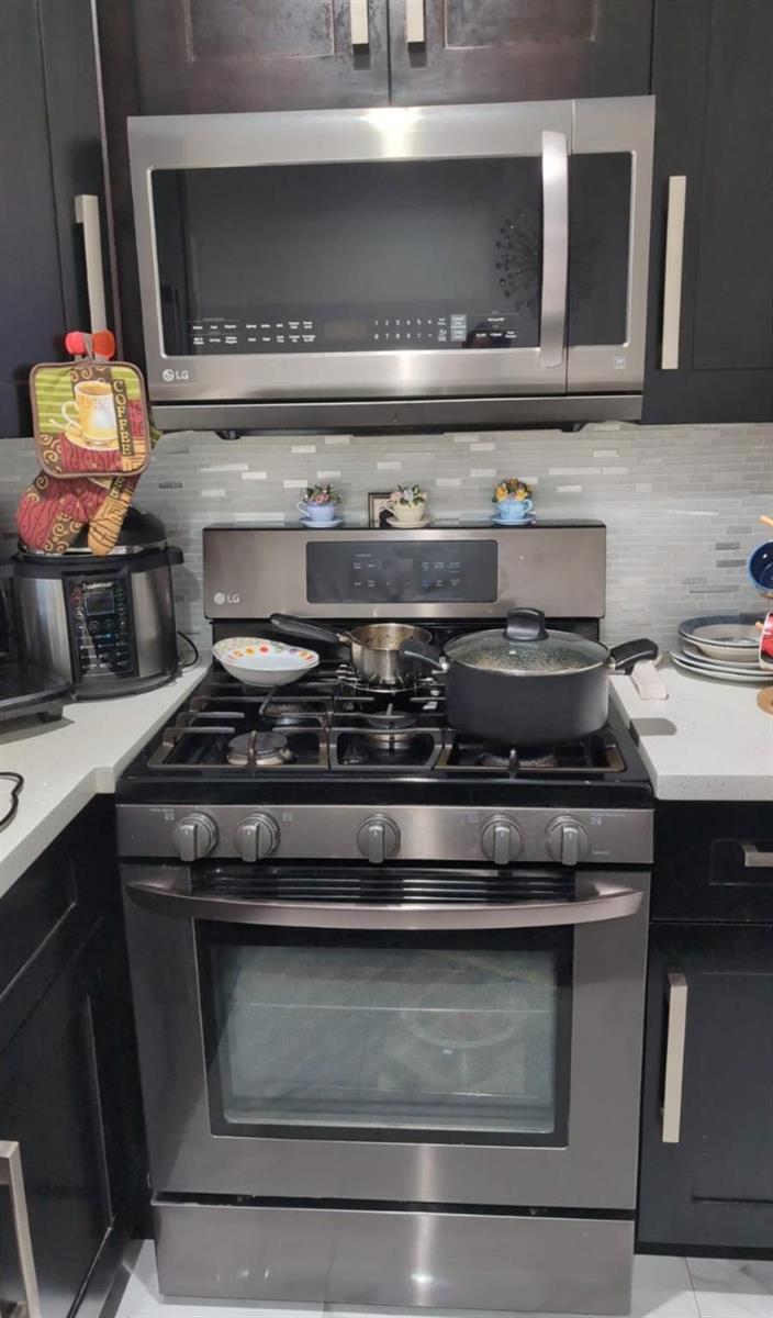 A kitchen features stainless steel LG appliances, dark cabinets, and a light-colored tiled backsplash — 4655 Palm Avenue, Hialeah FL 33012, HIALEAH, FL