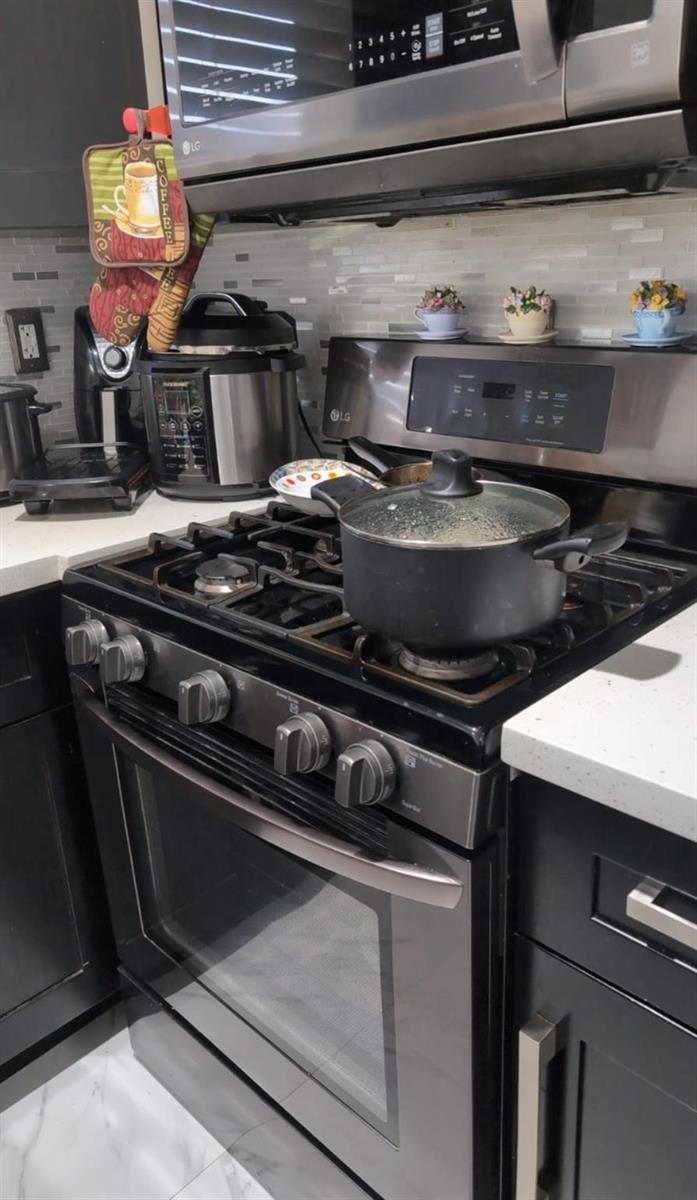 A kitchen features a stainless steel gas range, microwave, and dark cabinetry with white countertops — 4655 Palm Avenue, Hialeah FL 33012, HIALEAH, FL