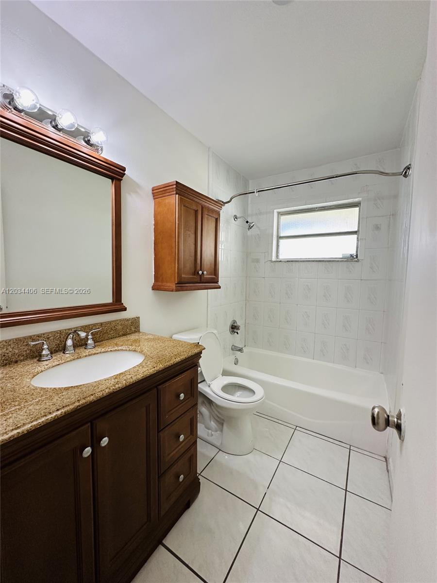 A bathroom features a wooden vanity with a granite countertop, toilet, and tiled shower-tub combo — 2319 Jackson St # 6, Hollywood FL 33020, HOLLYWOOD, FL