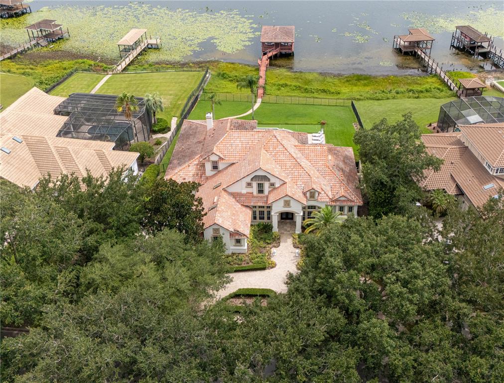 An aerial view shows a large house with a terracotta roof, pool, and private dock — 9233 SOUTHERN BREEZE DRIVE, ORLANDO, FL