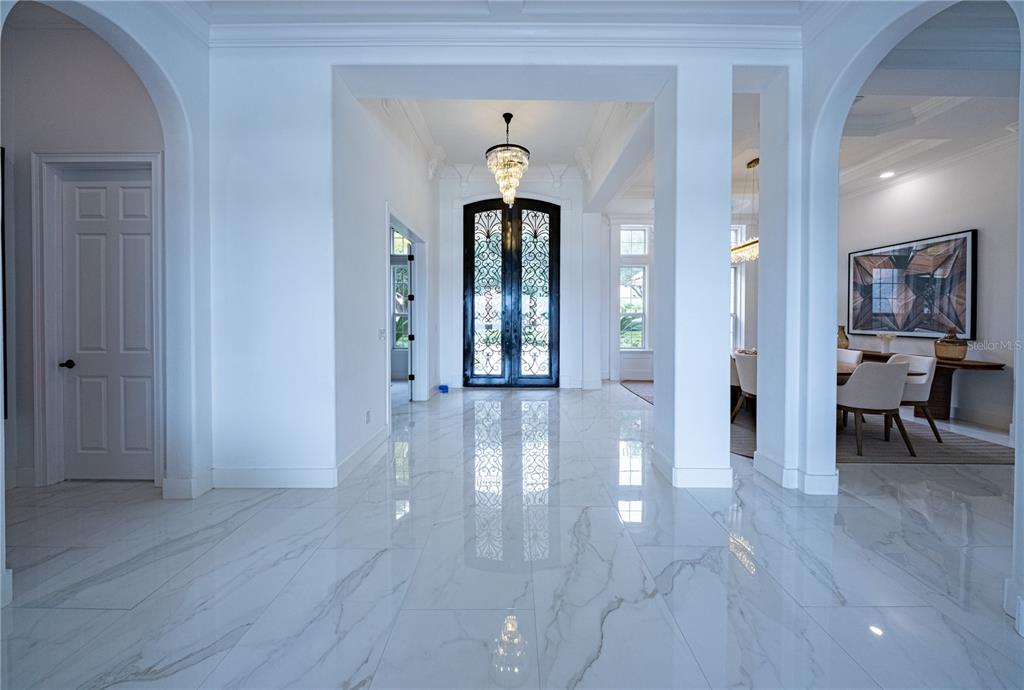 A bright foyer features white marble floors, arched doorways, and a decorative black double door — 9233 SOUTHERN BREEZE DRIVE, ORLANDO, FL