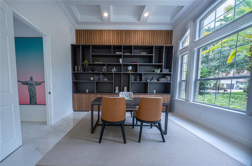 A home office features a large dark bookshelf, two leather chairs, and a coffered ceiling — 9233 SOUTHERN BREEZE DRIVE, ORLANDO, FL