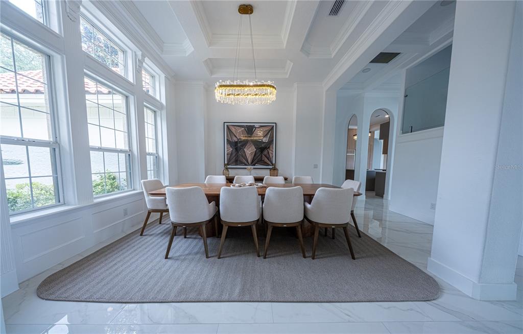 A dining room features a long wooden table, eight upholstered chairs, and a crystal chandelier — 9233 SOUTHERN BREEZE DRIVE, ORLANDO, FL