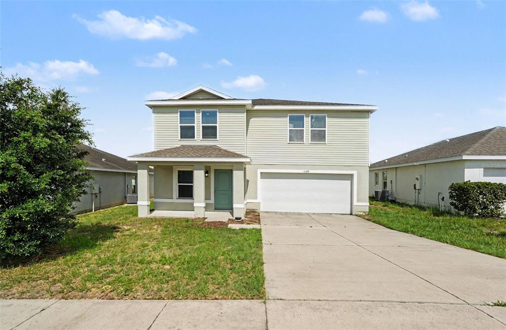 A two-story house with light siding, a front porch, and an attached two-car garage — 4189 HIGH RIDGE AVENUE, SPRING HILL, FL