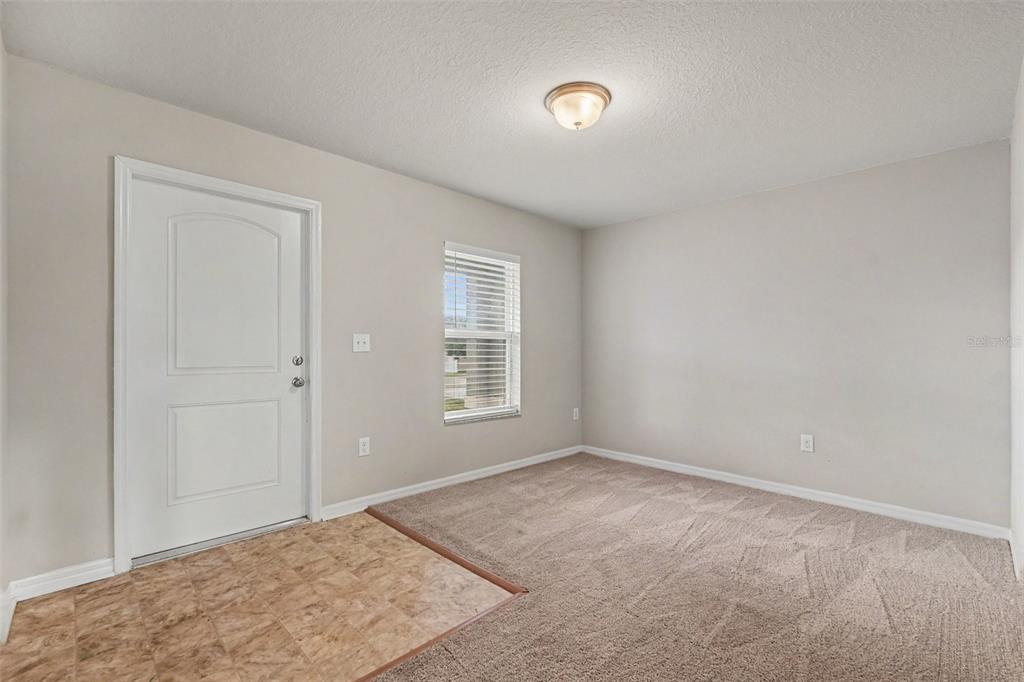 A room with a white door, a window with blinds, carpeted flooring, and vinyl tile — 4189 HIGH RIDGE AVENUE, SPRING HILL, FL