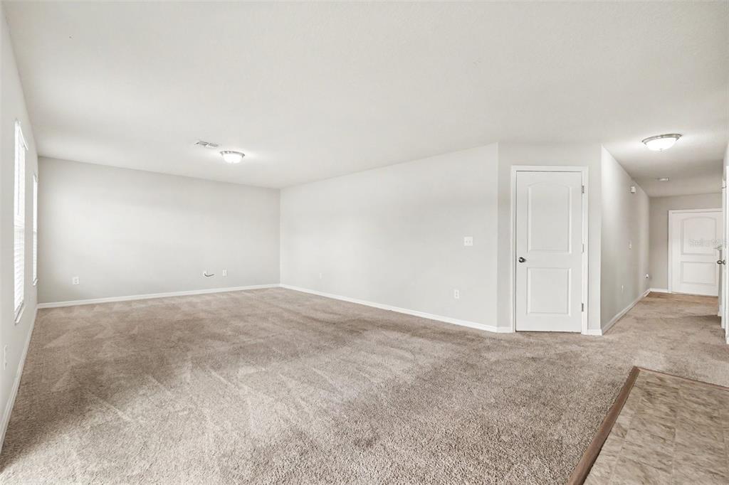 An empty room with beige carpet, light gray walls, and two white interior doors — 4189 HIGH RIDGE AVENUE, SPRING HILL, FL