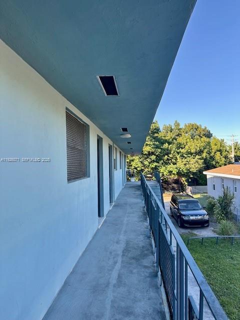 An exterior walkway with a metal railing overlooks a parking area and a neighboring house — 129 NE 80th Ter # 6, Miami FL 33138, MIAMI, FL