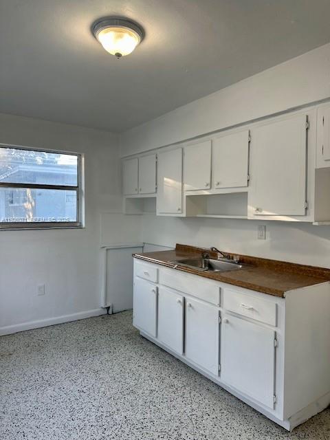 A kitchen features white cabinets, a brown countertop, a stainless steel sink, and speckled flooring — 129 NE 80th Ter # 6, Miami FL 33138, MIAMI, FL
