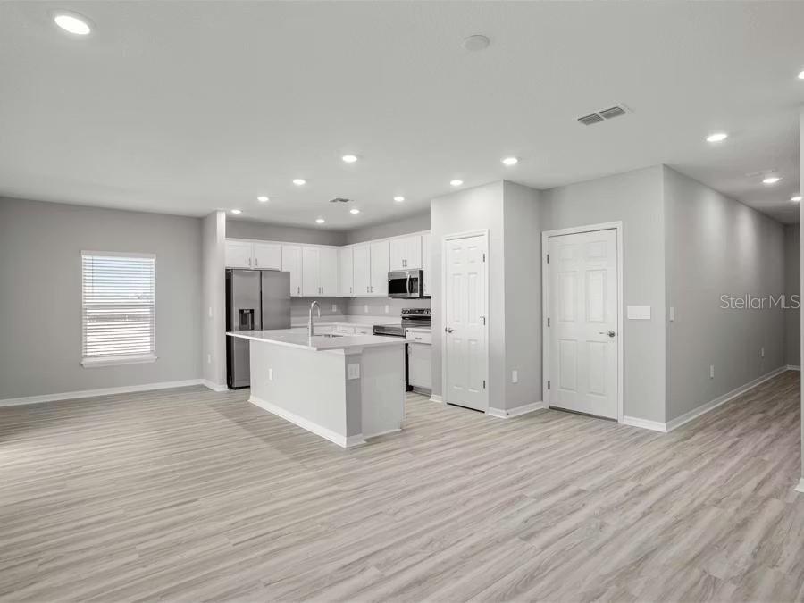 A modern kitchen with white cabinets, stainless steel appliances, and an island in an open-concept room — 5121 SYLAS JAX AVENUE, WINTER HAVEN, FL