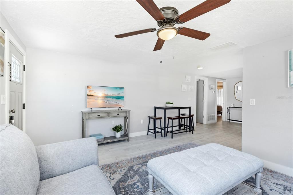 A living room features a gray sofa, a ceiling fan, and a small dining table — 5320 MOELLER AVENUE, SARASOTA, FL