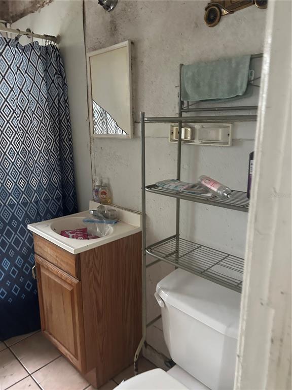 A bathroom features a wooden vanity, a toilet with a metal shelf, and a shower curtain — 2018 BRACKLAND STREET, JACKSONVILLE, FL