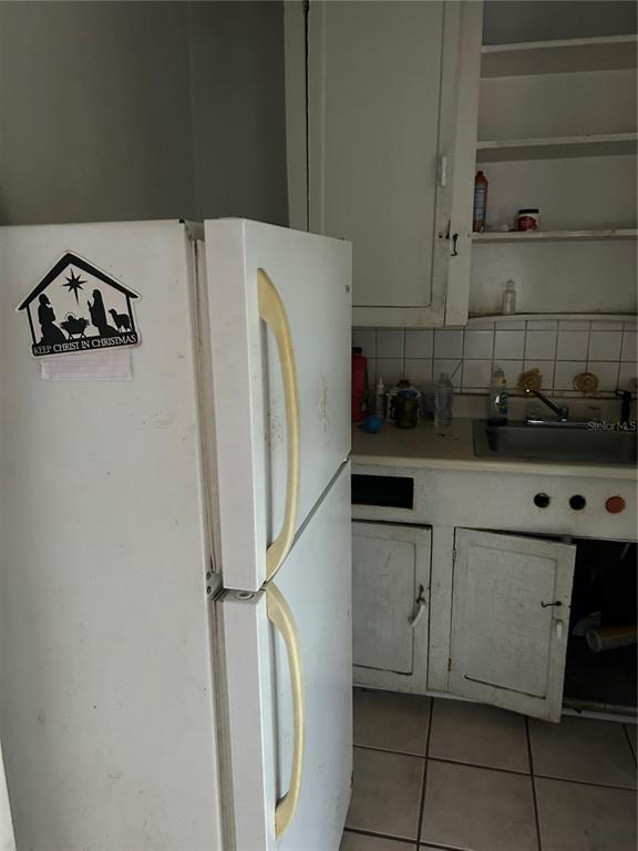 A kitchen features a white refrigerator, a sink, and worn white wooden cabinets — 2018 BRACKLAND STREET, JACKSONVILLE, FL
