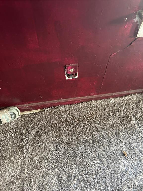 A close-up view of a red wall with a damaged electrical outlet and a crack — 2018 BRACKLAND STREET, JACKSONVILLE, FL