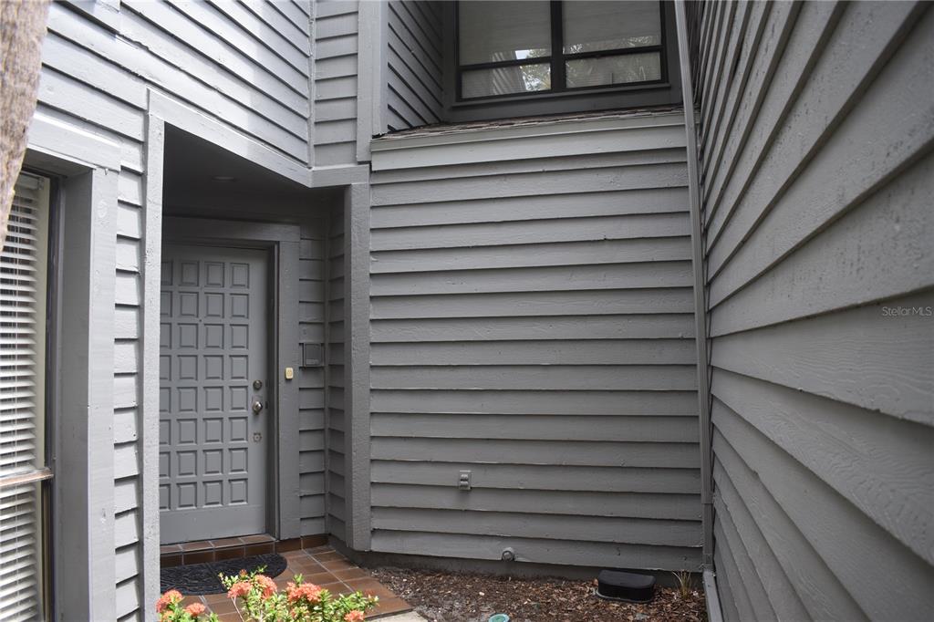 The exterior entrance features a gray door, horizontal siding, and a tiled porch area — 3053 EAGLES LANDING CIRCLE W UNIT 3053, CLEARWATER, FL
