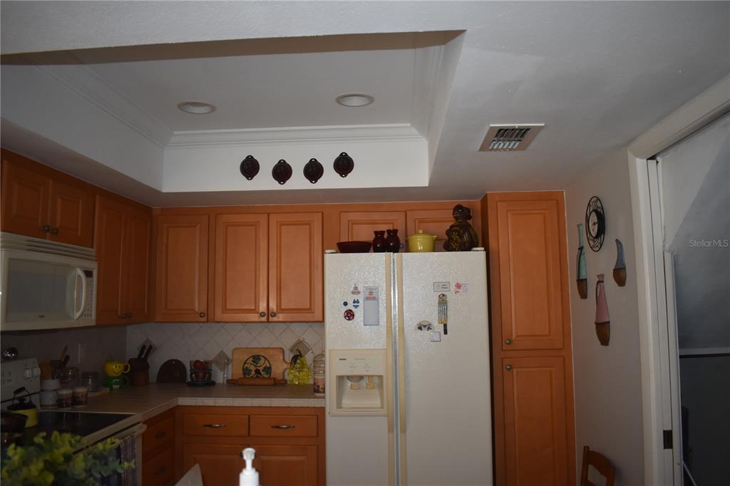 A kitchen features light wood cabinets, a white refrigerator, and a recessed ceiling area — 3053 EAGLES LANDING CIRCLE W UNIT 3053, CLEARWATER, FL
