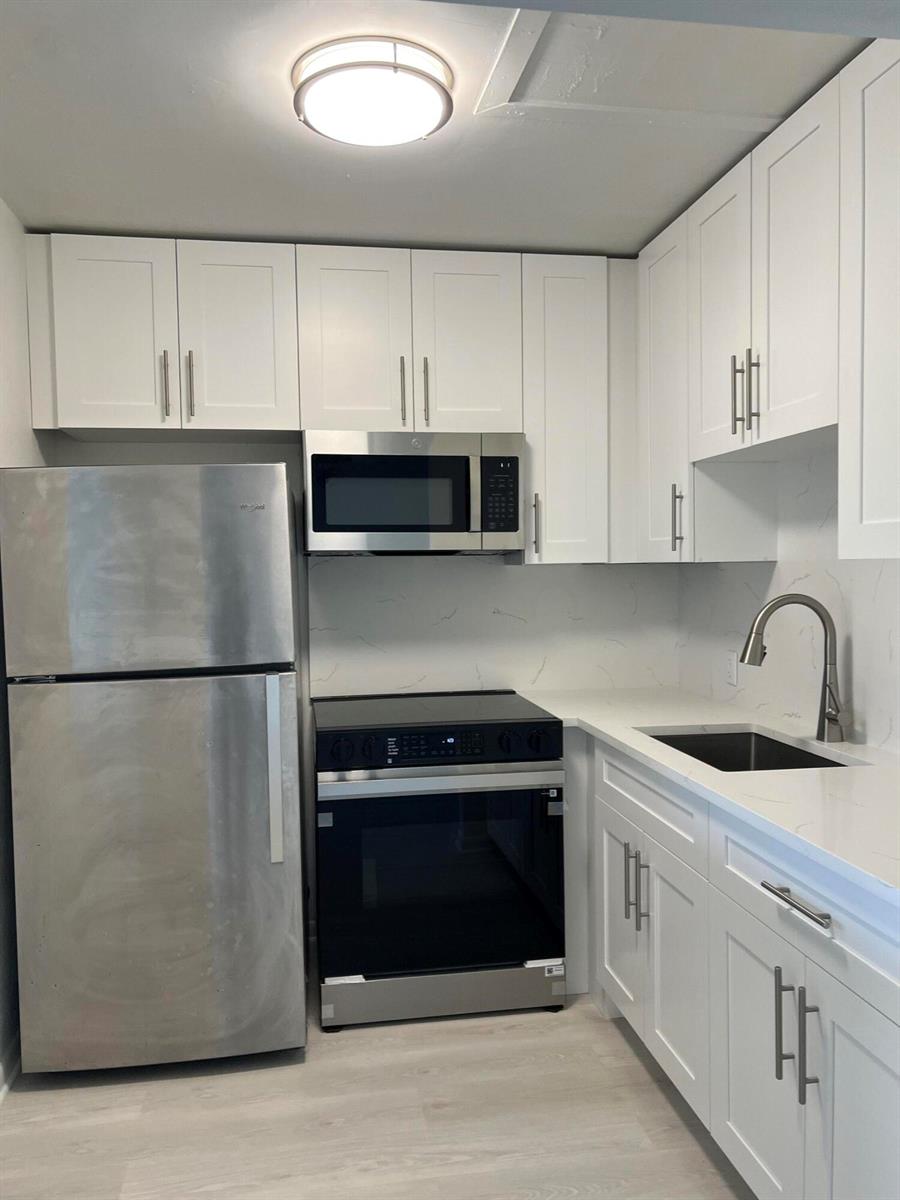 A kitchen features white cabinets, stainless steel appliances, and white countertops with a backsplash — 36 Mansfield A, Boca Raton FL 33434, BOCA RATON, FL