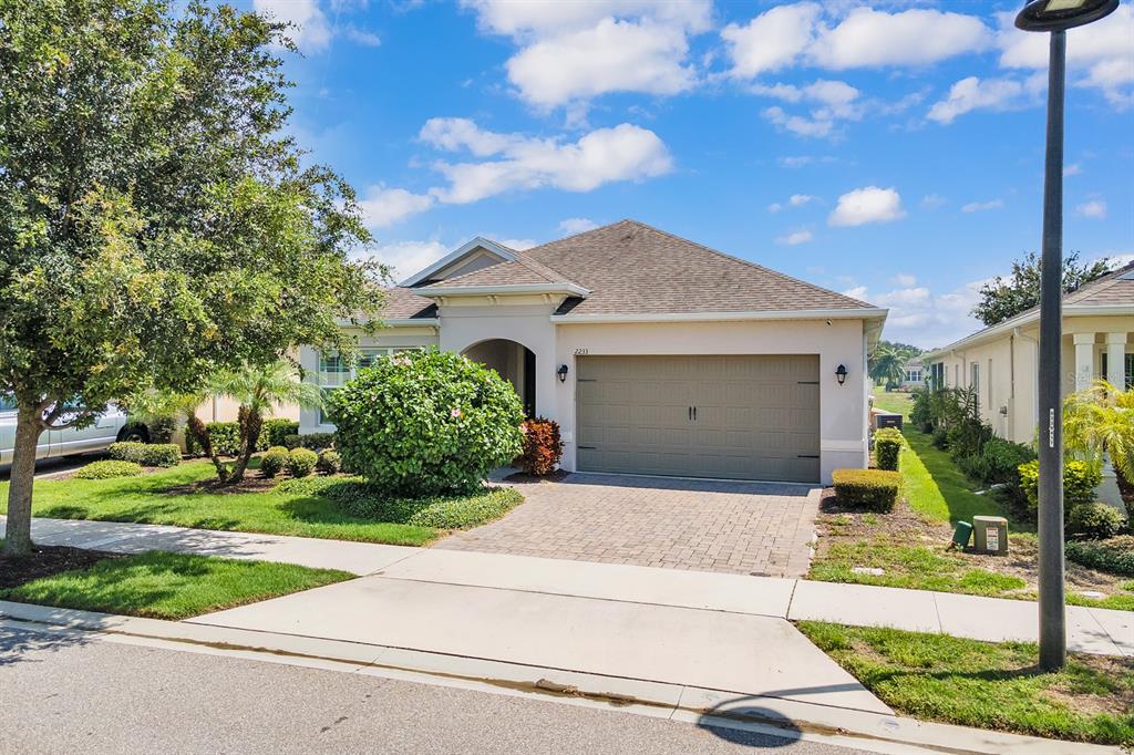 A single-story house with a beige exterior, a two-car garage, and a paved driveway — 2233 ANTILLES CLUB DRIVE, KISSIMMEE, FL