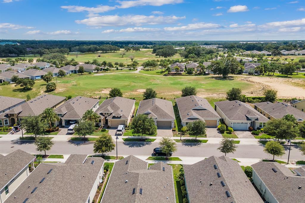 An aerial view shows a suburban neighborhood with houses facing a large golf course — 2233 ANTILLES CLUB DRIVE, KISSIMMEE, FL