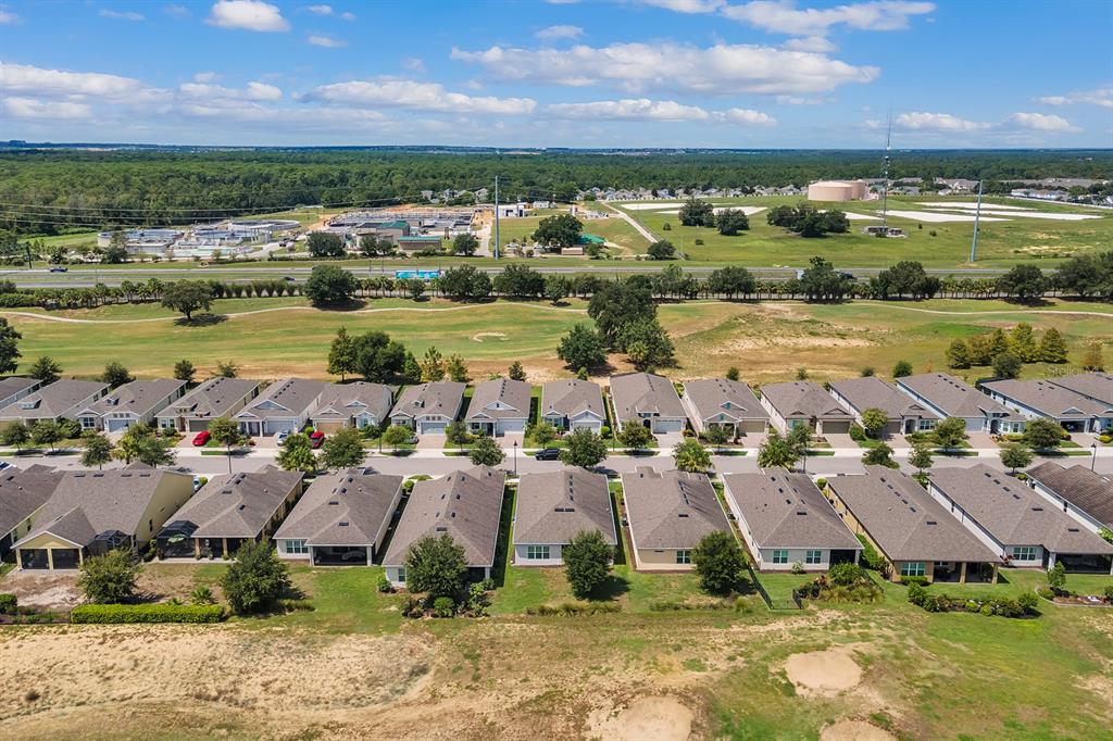 An aerial view shows a row of suburban houses bordering a golf course and highway — 2233 ANTILLES CLUB DRIVE, KISSIMMEE, FL