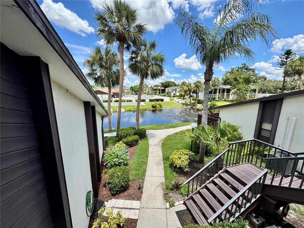 An outdoor view from a balcony overlooking a pond, palm trees, and a walkway — 5400 34TH STREET W UNIT 12H, BRADENTON, FL