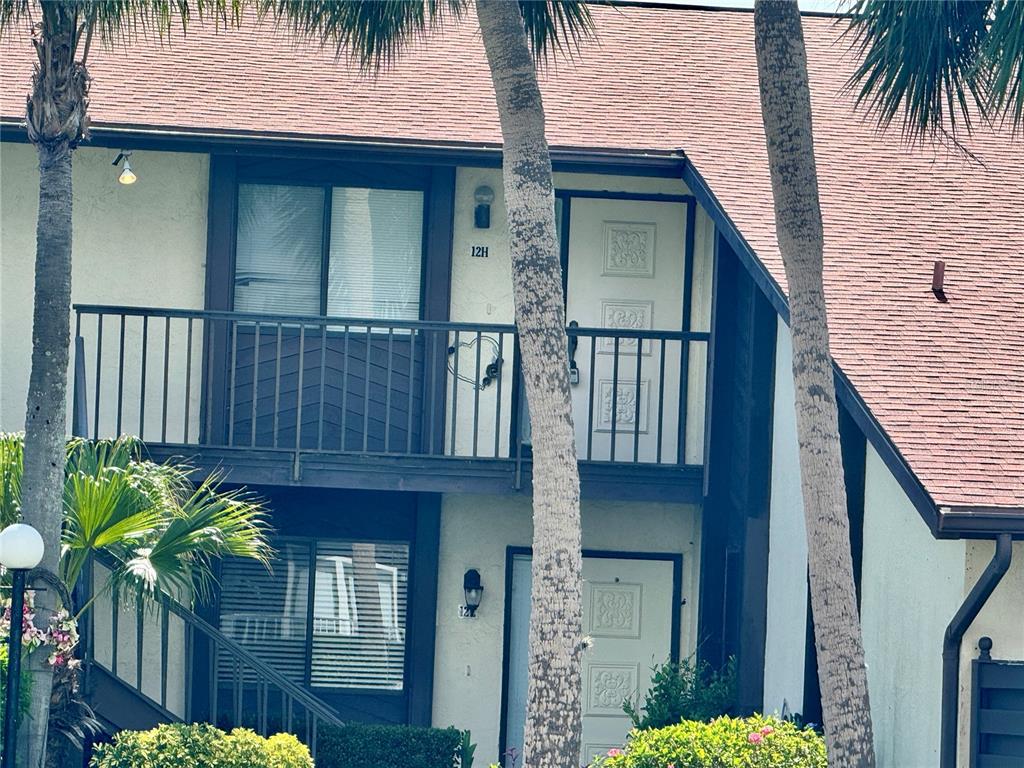 The exterior of a two-story residential building features a balcony and a ground-level entrance — 5400 34TH STREET W UNIT 12H, BRADENTON, FL