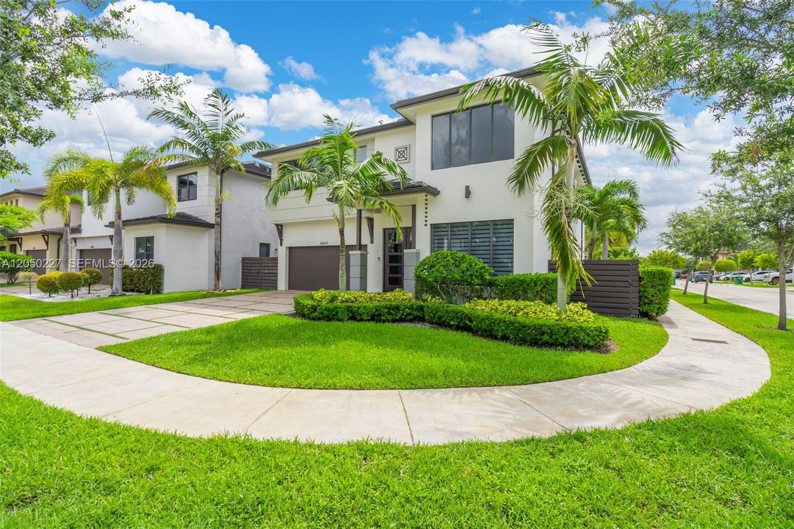 A two-story modern house with a paved driveway, palm trees, and a landscaped front yard — 15455 NW 88th Ct, Miami Lakes FL 33018, MIAMI LAKES, FL