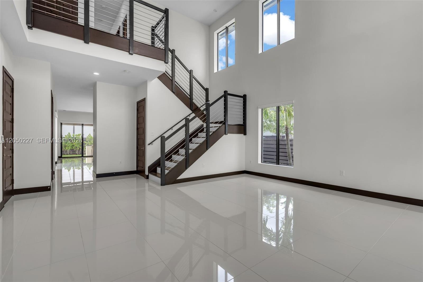 A modern foyer features white tile floors, a dark wood staircase, and high ceilings — 15455 NW 88th Ct, Miami Lakes FL 33018, MIAMI LAKES, FL