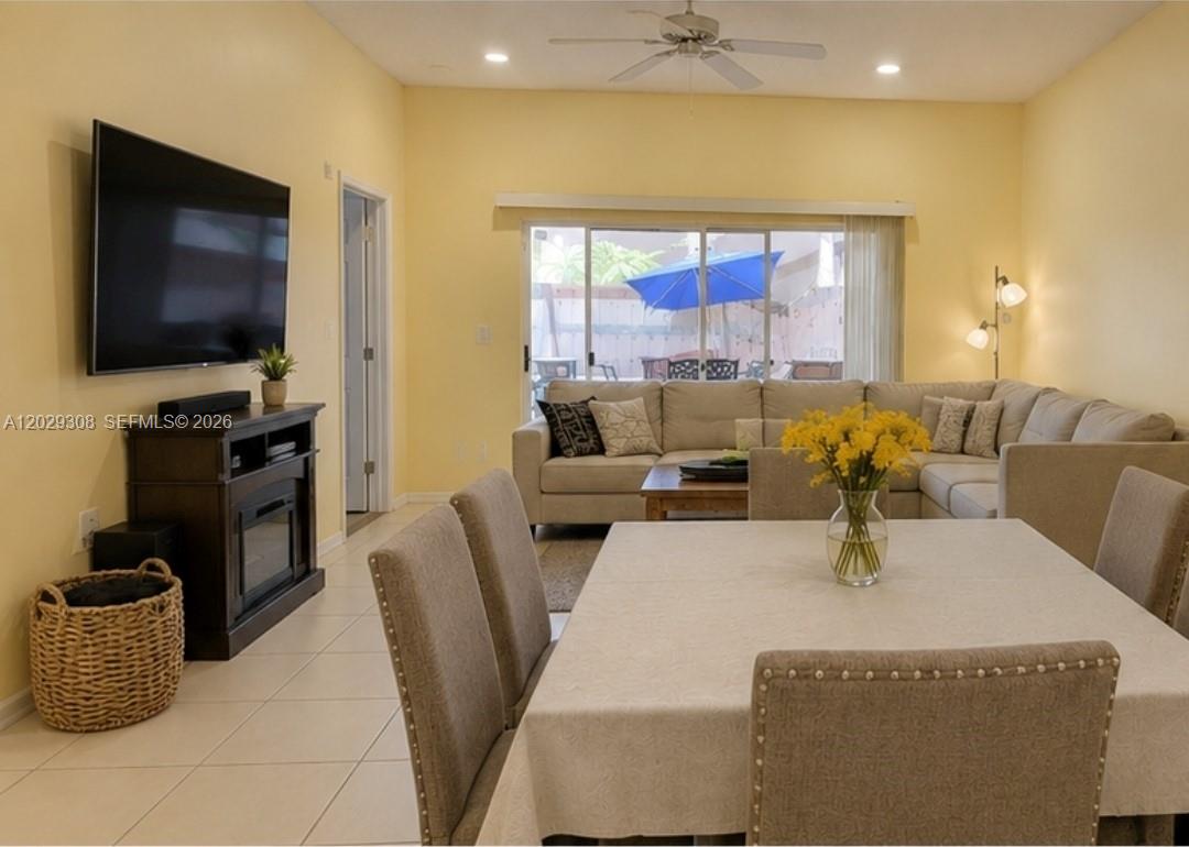 A living and dining area features yellow walls, tile flooring, a sectional sofa, and a television — 16143 Emerald Cove Rd, Weston FL 33331, WESTON, FL