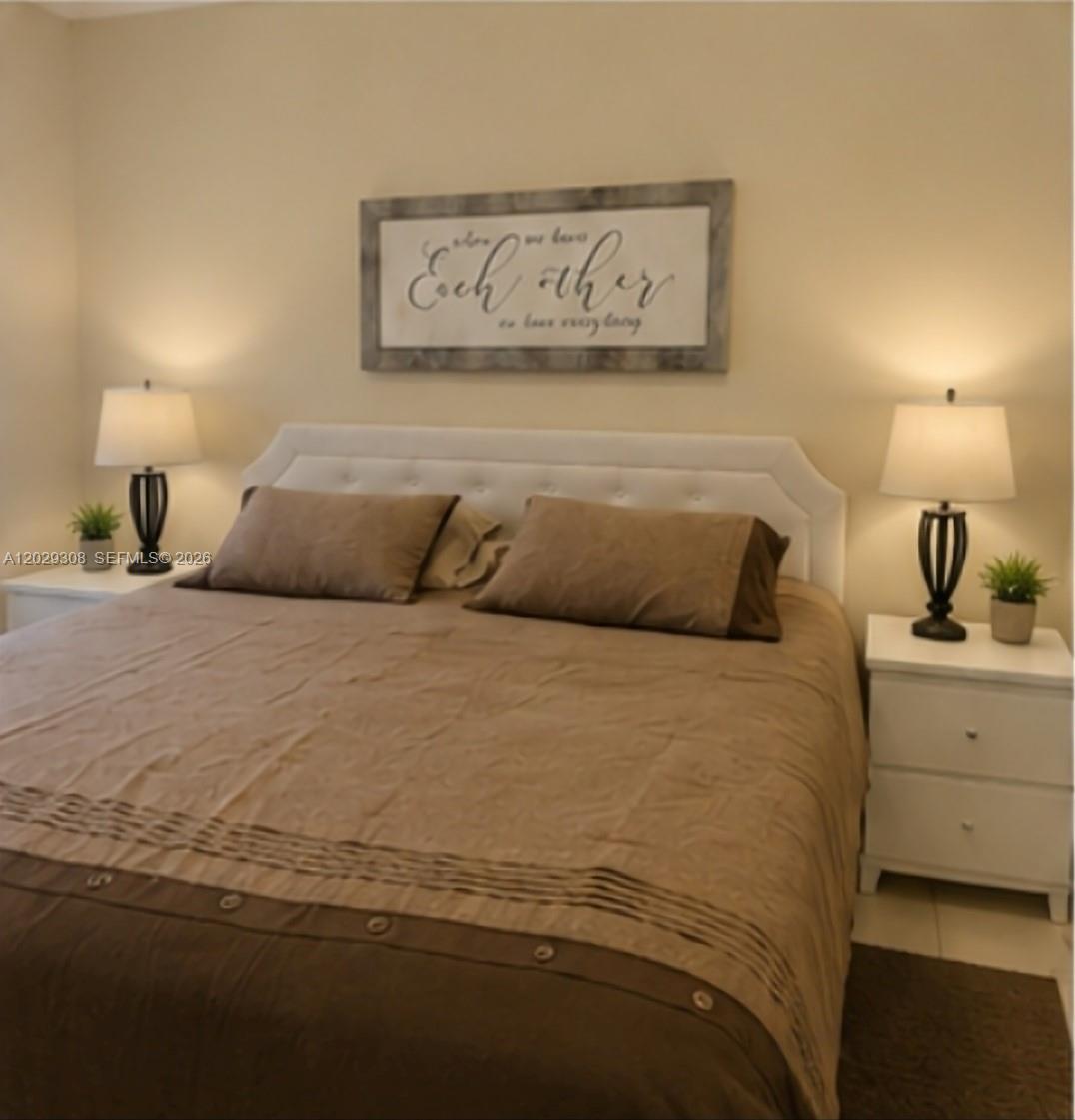 A bedroom features a bed with a tan comforter, white headboard, and two matching nightstands — 16143 Emerald Cove Rd, Weston FL 33331, WESTON, FL