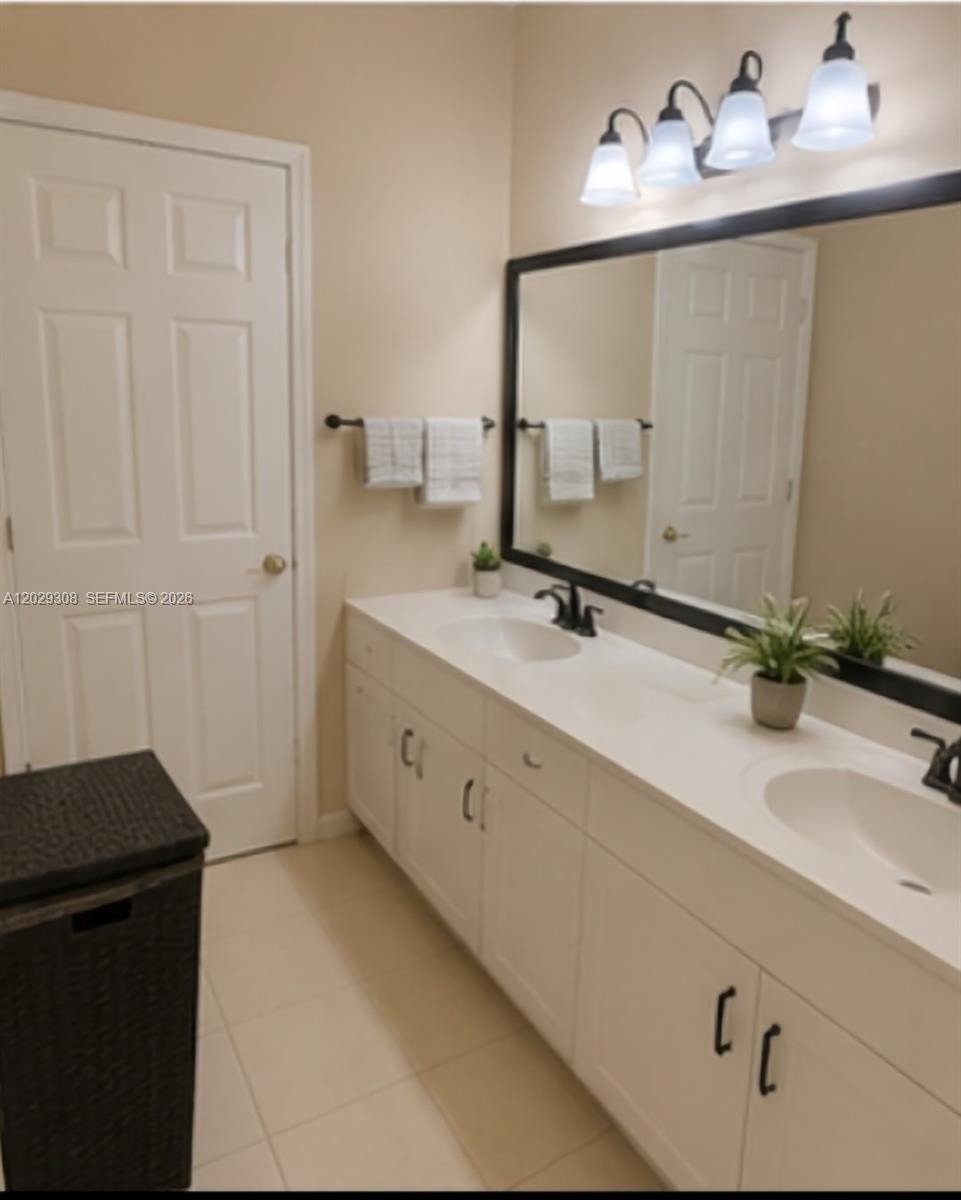 A bathroom features a double vanity with white cabinets, black hardware, and a large mirror — 16143 Emerald Cove Rd, Weston FL 33331, WESTON, FL