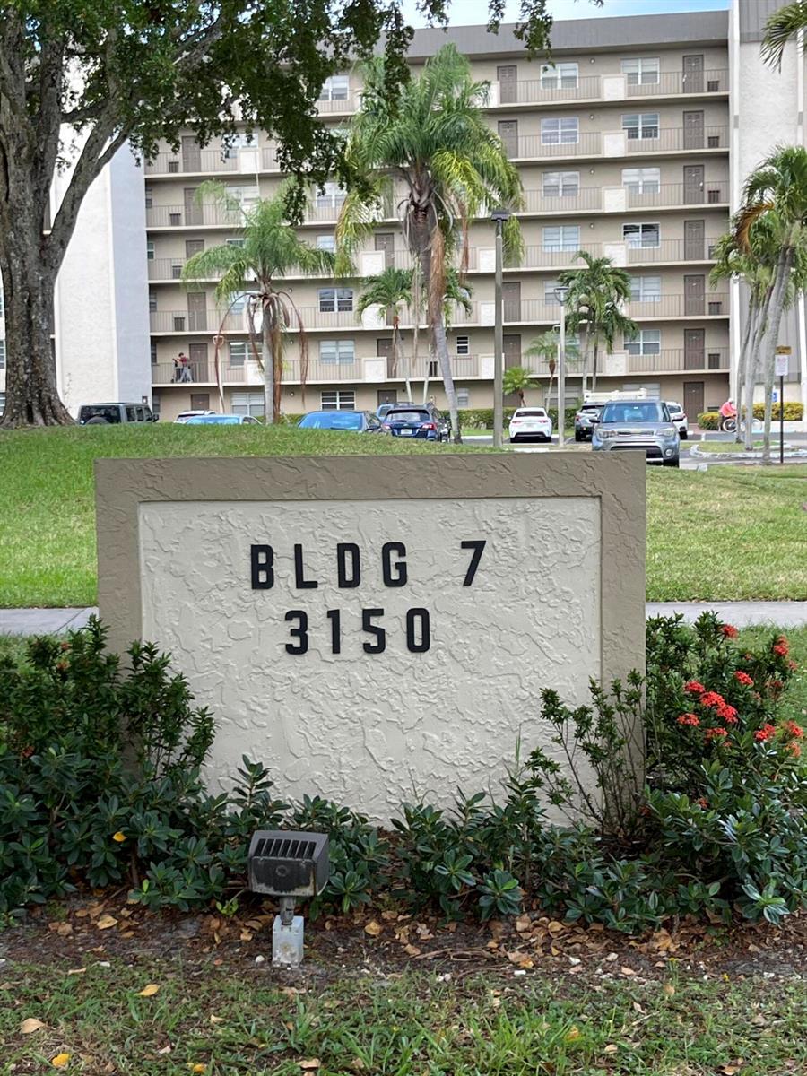 A sign for Building 7 stands in front of a multi-story apartment complex with palm trees — 3150 W Rolling Hills Circle # 704, Davie FL 33328, DAVIE, FL