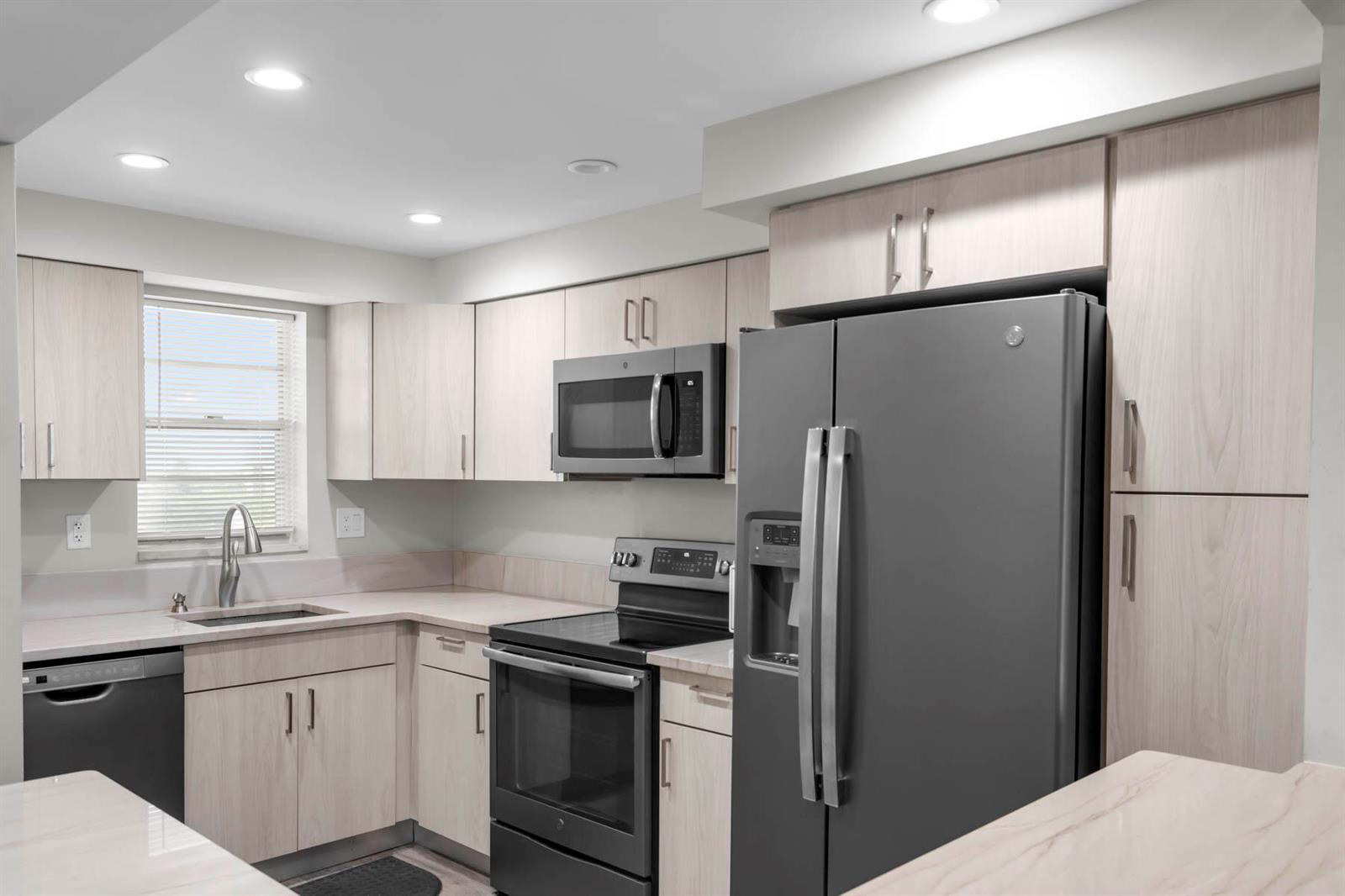 A kitchen features light wood cabinets, stainless steel appliances, and a window above the sink — 3150 W Rolling Hills Circle # 704, Davie FL 33328, DAVIE, FL